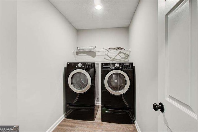 clothes washing area featuring a textured ceiling, laundry area, washing machine and dryer, and baseboards