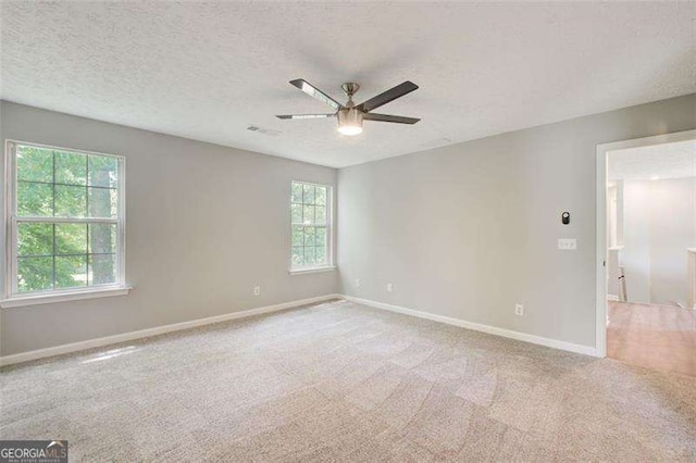 empty room with carpet, visible vents, baseboards, and a textured ceiling