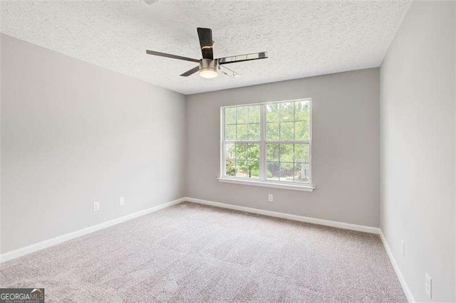 spare room with a textured ceiling, carpet flooring, a ceiling fan, and baseboards