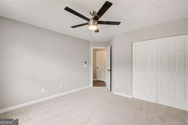 unfurnished bedroom with baseboards, ceiling fan, a textured ceiling, carpet flooring, and a closet