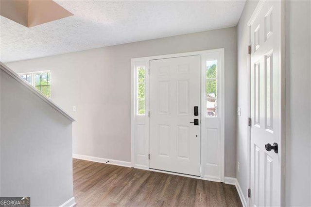 entrance foyer featuring a textured ceiling, baseboards, and dark wood-type flooring