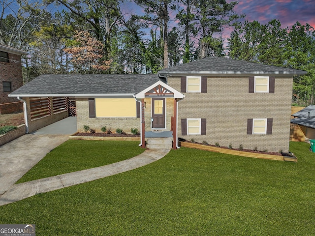 split level home featuring an attached carport, brick siding, a lawn, and driveway