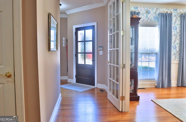 entrance foyer with visible vents, baseboards, crown molding, and wood finished floors