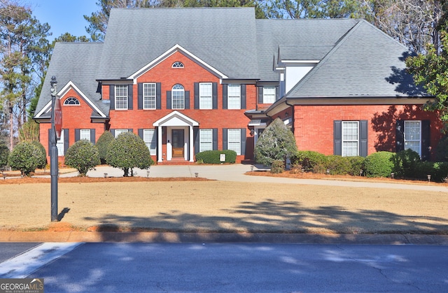 view of front of home featuring brick siding and roof with shingles