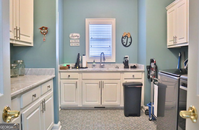 kitchen with white cabinetry, washer and clothes dryer, and a sink