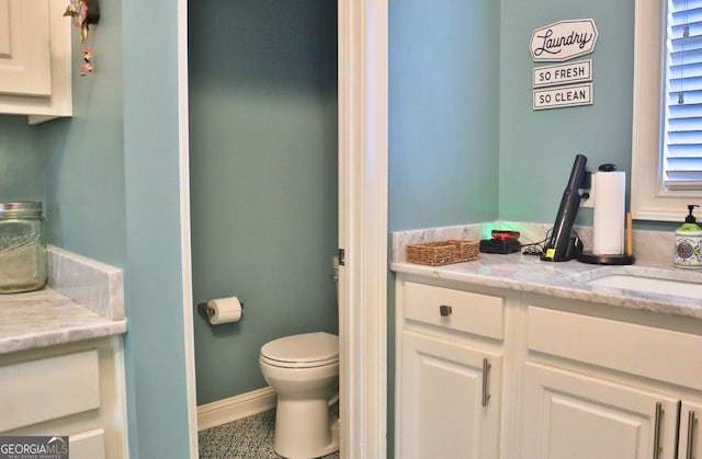 bathroom featuring toilet, vanity, and baseboards