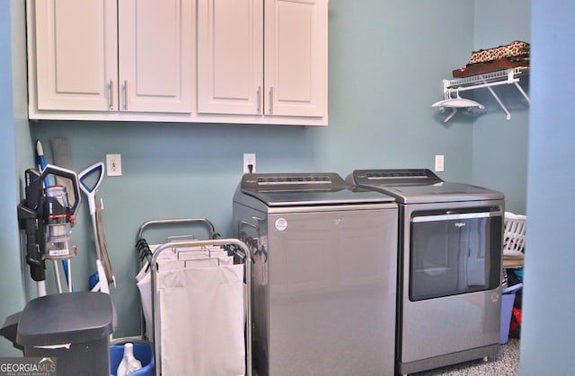 clothes washing area featuring washing machine and clothes dryer and cabinet space