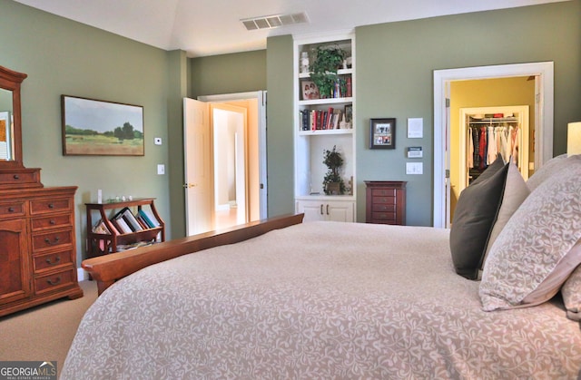 bedroom with carpet floors, visible vents, a walk in closet, and a closet