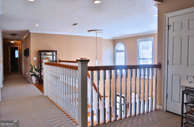 hall with a textured ceiling, recessed lighting, visible vents, baseboards, and crown molding