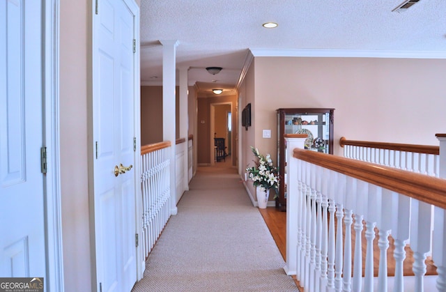 corridor featuring a textured ceiling, visible vents, and crown molding