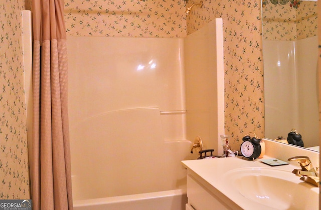 full bath featuring shower / bathtub combination with curtain, vanity, and wallpapered walls