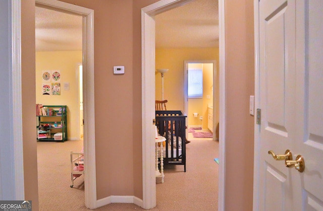 hall featuring carpet, baseboards, and an upstairs landing