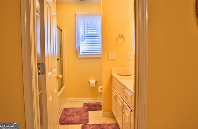 full bath featuring baseboards, toilet, shower / bath combination with glass door, tile patterned flooring, and vanity