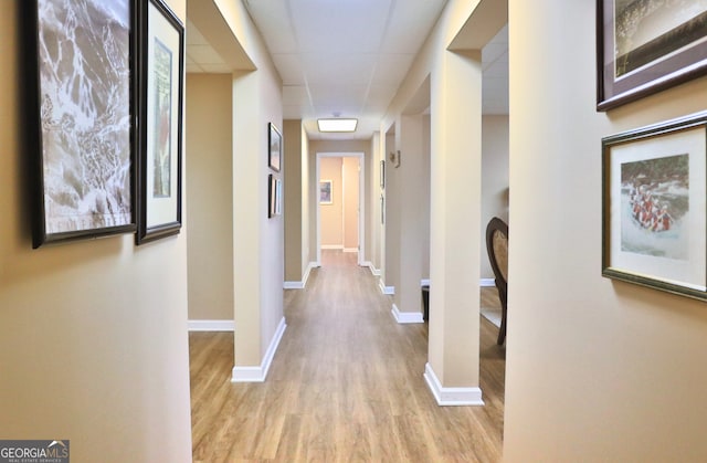 corridor with baseboards and wood finished floors