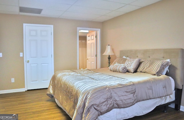 bedroom with a paneled ceiling, baseboards, and wood finished floors