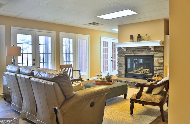 living room featuring french doors, a fireplace, wood finished floors, and visible vents