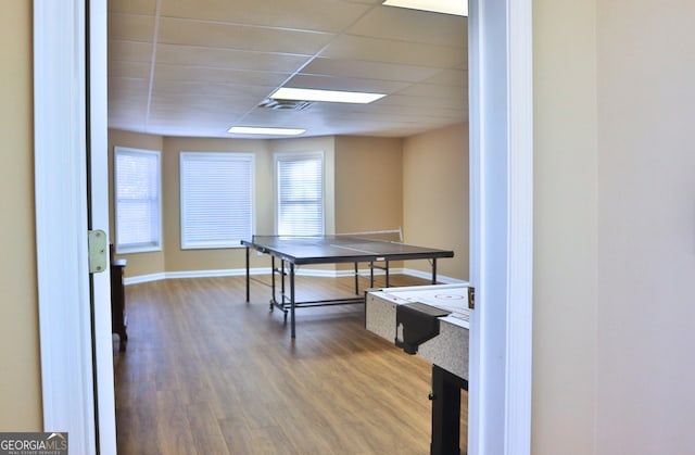 recreation room featuring a paneled ceiling, a wealth of natural light, baseboards, and wood finished floors