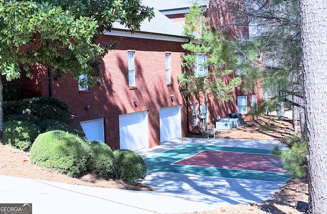 view of side of property featuring a garage, concrete driveway, and brick siding