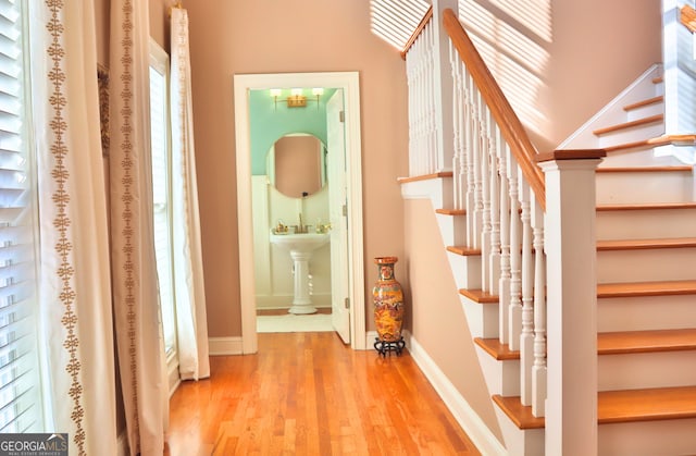 corridor with stairs, a healthy amount of sunlight, baseboards, and wood finished floors