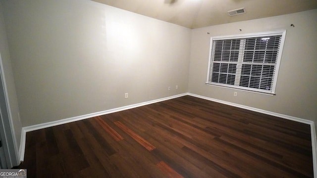 spare room featuring lofted ceiling, dark wood-type flooring, visible vents, and baseboards