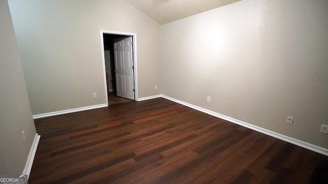 unfurnished room featuring dark wood-style floors, lofted ceiling, and baseboards