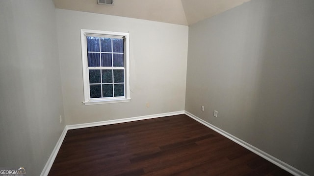 unfurnished room featuring lofted ceiling, baseboards, visible vents, and dark wood finished floors