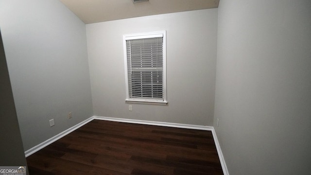 unfurnished room with baseboards and dark wood finished floors