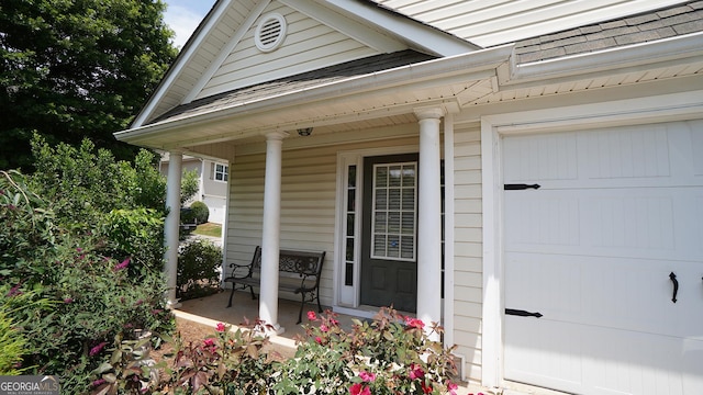 entrance to property featuring covered porch and an attached garage