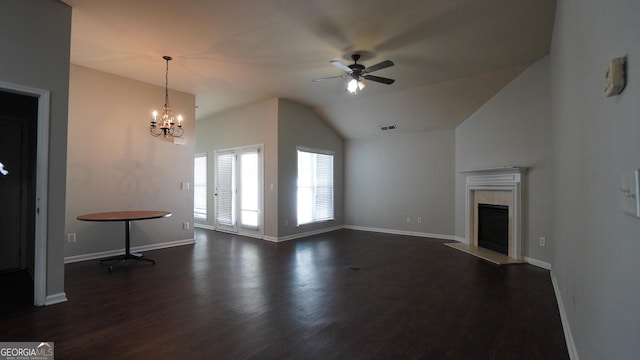 unfurnished living room featuring dark wood-style floors, lofted ceiling, a tiled fireplace, baseboards, and ceiling fan with notable chandelier