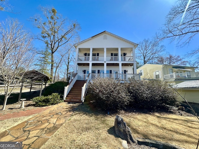 rear view of property featuring stairway and a balcony