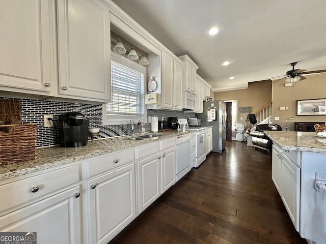 kitchen with white appliances, tasteful backsplash, white cabinets, dark wood-type flooring, and a sink