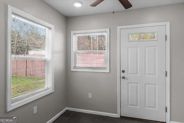 entryway featuring baseboards, a ceiling fan, and dark tile patterned flooring