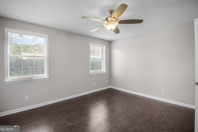 spare room featuring a textured ceiling, dark wood finished floors, a ceiling fan, and baseboards