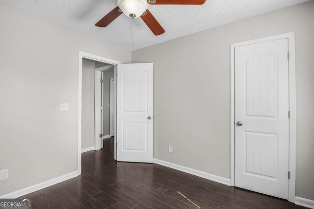 unfurnished bedroom with dark wood-style floors, a textured ceiling, and baseboards