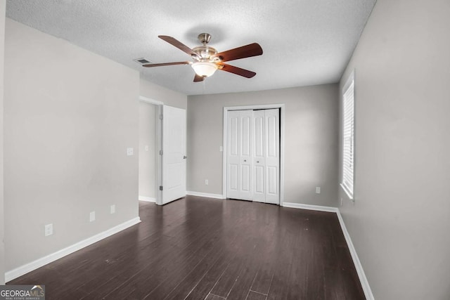 unfurnished bedroom with baseboards, ceiling fan, wood finished floors, a textured ceiling, and a closet