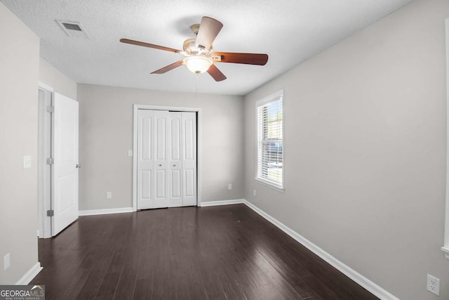 unfurnished bedroom featuring a closet, visible vents, dark wood finished floors, and baseboards