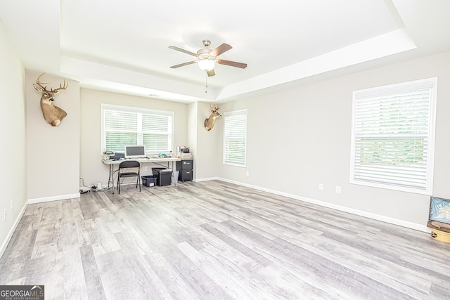 home office with wood finished floors, a raised ceiling, and baseboards