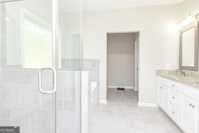 bathroom featuring tile patterned floors, baseboards, tiled shower, and vanity