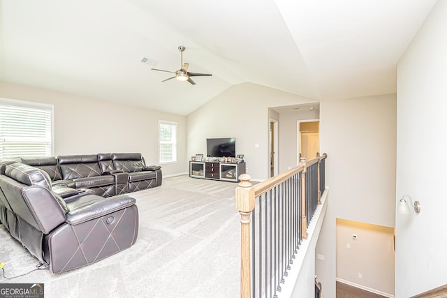 living area featuring carpet floors, lofted ceiling, visible vents, a ceiling fan, and baseboards