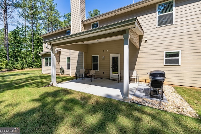 rear view of house featuring a patio area, a yard, and a chimney