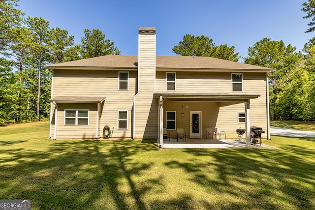 rear view of property featuring a patio area, a yard, and a chimney