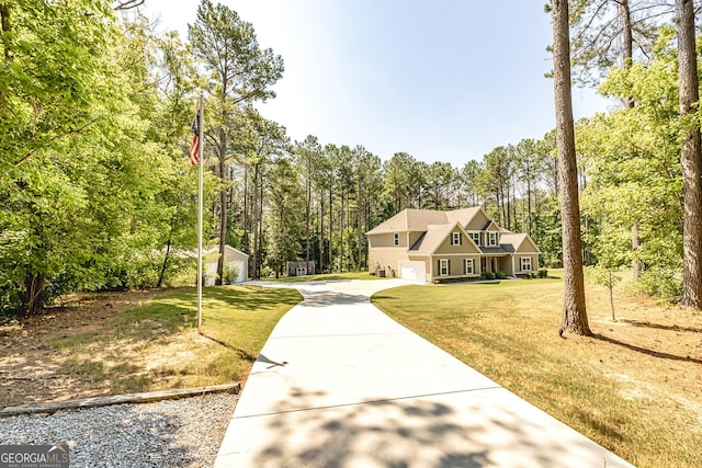 view of front facade featuring an attached garage, driveway, a wooded view, and a front yard