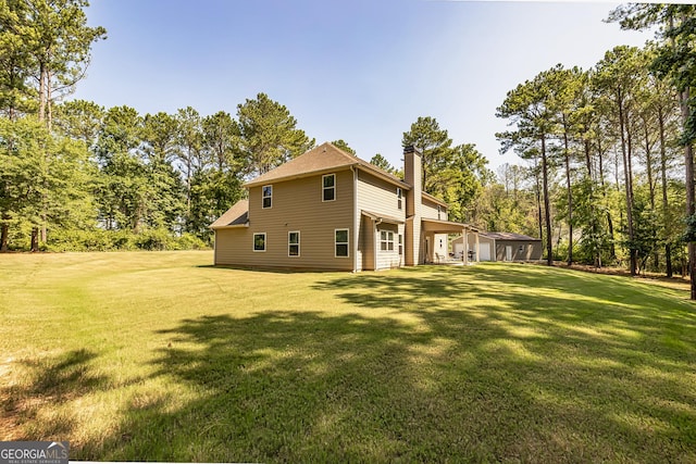 back of house with a yard and a chimney