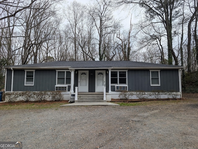 view of front of house with a porch, driveway, roof with shingles, board and batten siding, and a chimney