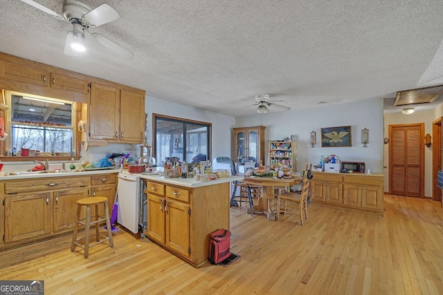 kitchen with ceiling fan, a peninsula, light countertops, and light wood-style floors