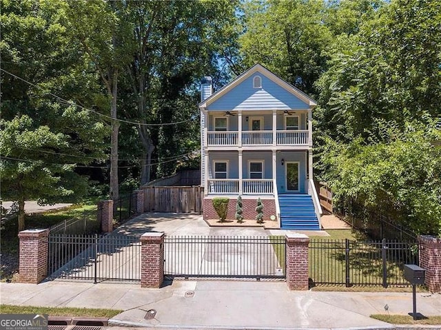 neoclassical home featuring a balcony, a fenced front yard, covered porch, stairs, and a gate