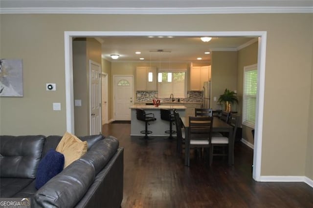 living area with a healthy amount of sunlight, baseboards, dark wood-type flooring, and crown molding