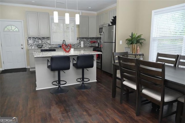 kitchen with a healthy amount of sunlight, a kitchen bar, ornamental molding, and freestanding refrigerator