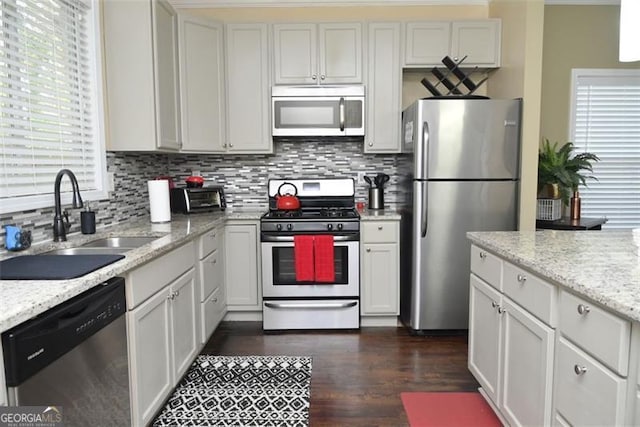 kitchen with stainless steel appliances, tasteful backsplash, dark wood-type flooring, and a sink