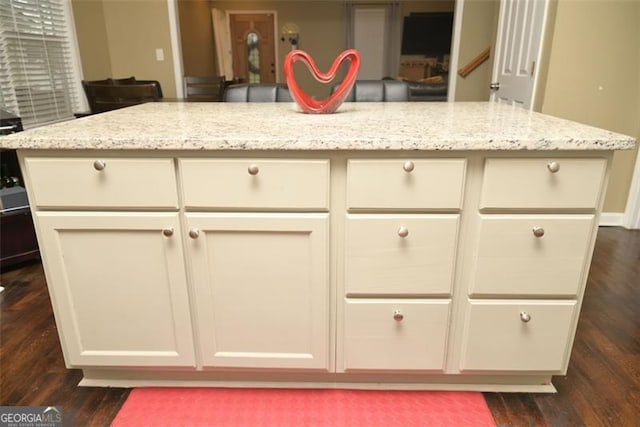 kitchen featuring light stone counters, white cabinets, a kitchen island, and dark wood-style floors